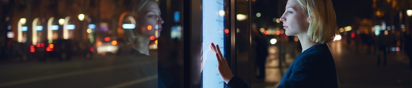 blonde woman touching digital sign city night