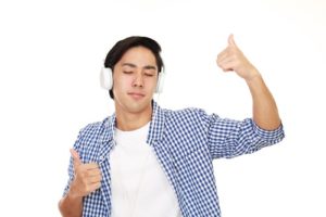 young man listening to music with headphones giving thumbs up