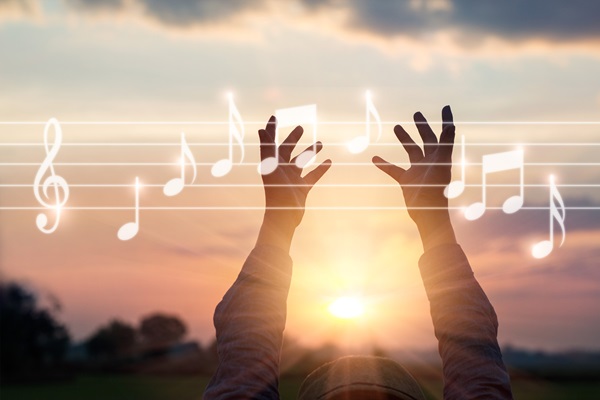 man with hands up at sunrise music staff